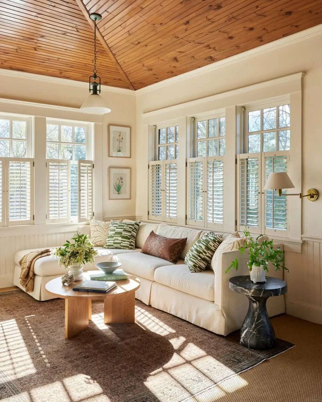 A sunlit corner shows how wood, woven texture, and soft cushions work together.