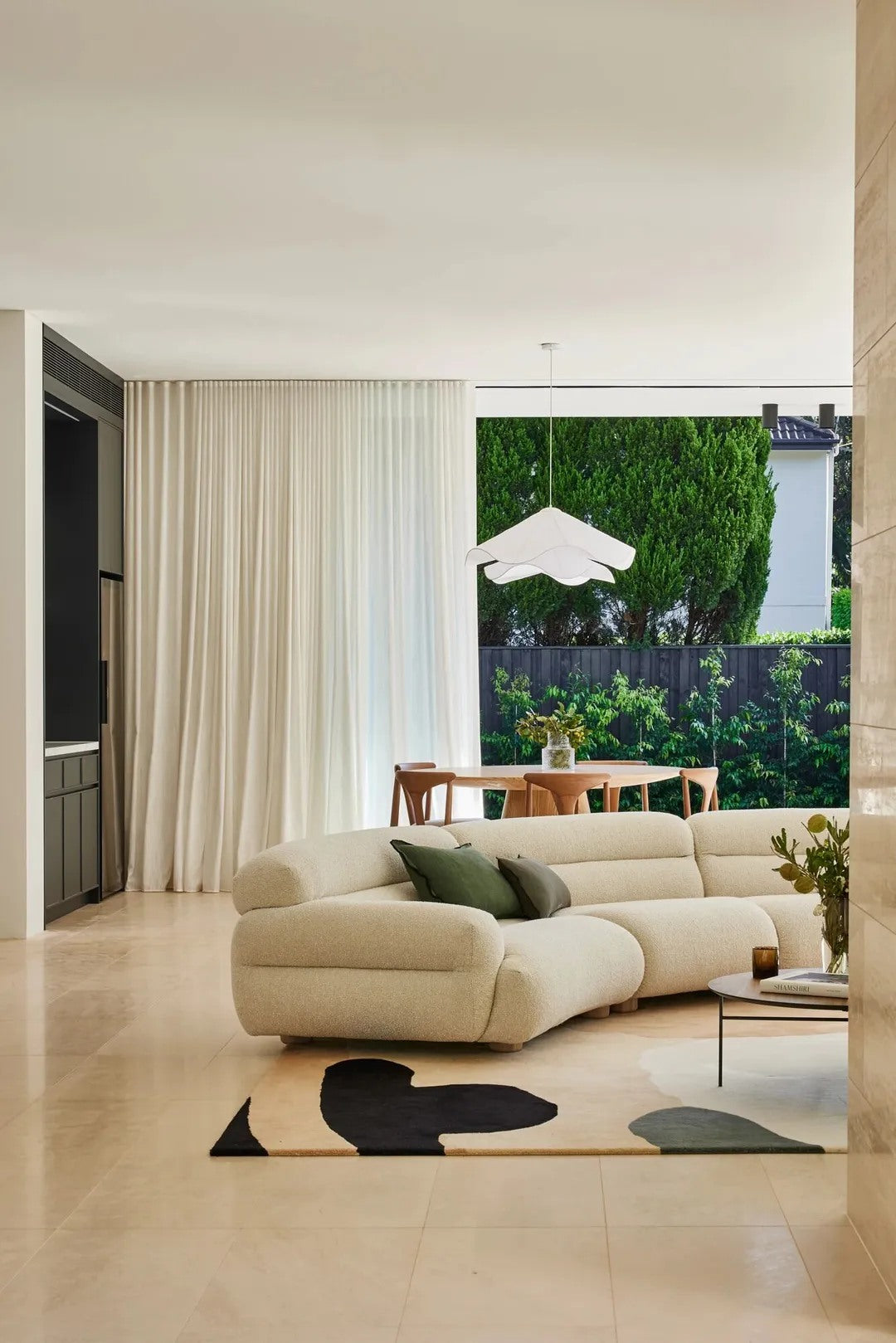 A low, rounded sofa lets the rug and negative space shape the room.