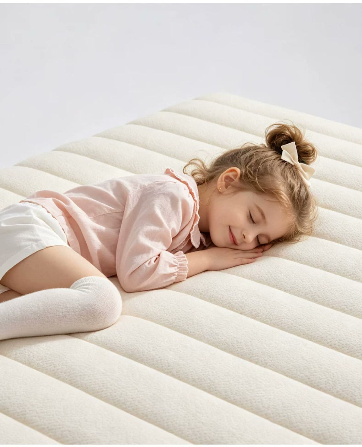  Child resting on the cream quilted surface of the mattress in a lifestyle scene