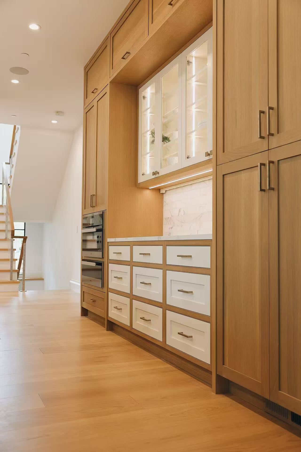 Tall kitchen storage and drawer wall in warm timber cabinetry