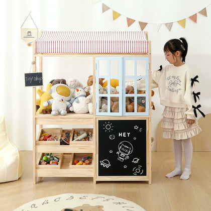  Child beside the play shop with a pale blue window swung open