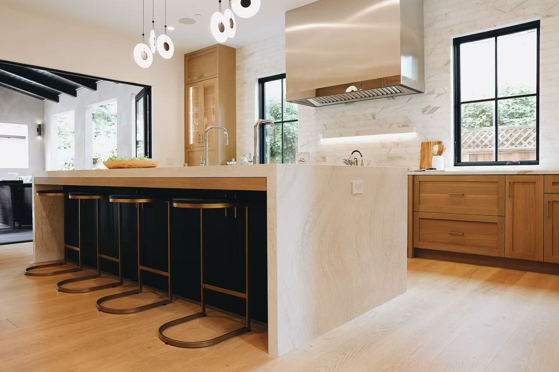 Kitchen island with black base, bar stools, stone waterfall side, and pendant lighting