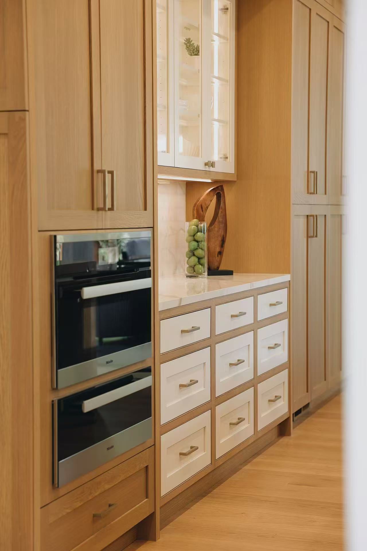 Vertical kitchen storage wall with built-in ovens and warm timber cabinet fronts