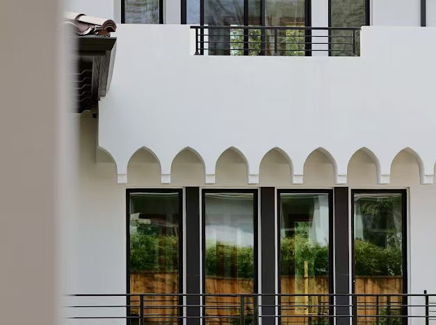 Exterior detail with white stucco arches and black framed windows
