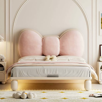  Front view of a cream wood bed with a pale pink bow upholstered headboard and rounded legs.