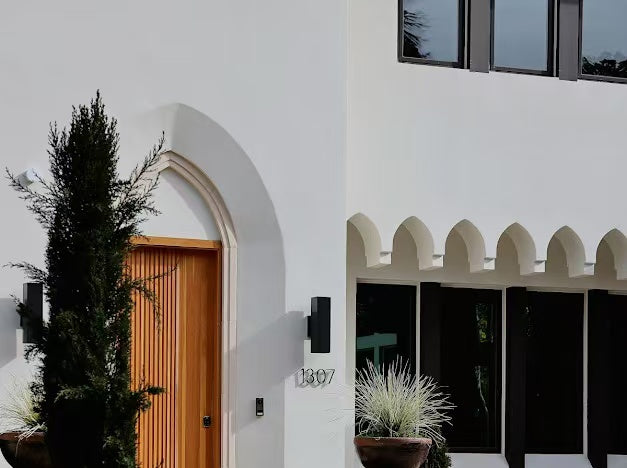 Front entry with arched timber door and white stucco facade