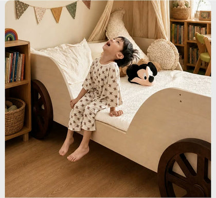  Child seated at the curved side opening of the cream car bed.