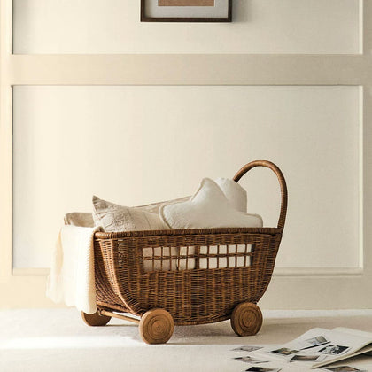  Woven trolley holding a cream blanket and cushions.