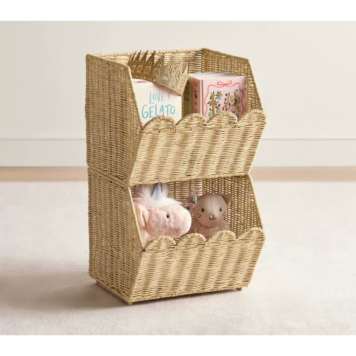 Two stacked scalloped rattan baskets holding books and soft toys.