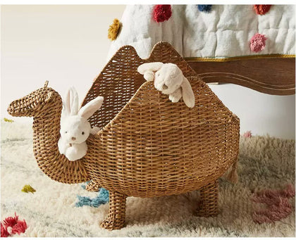  Camel basket holding soft toys beside a bed.