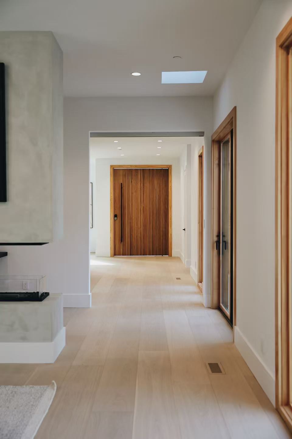 Bright hallway with pale flooring and warm timber doors