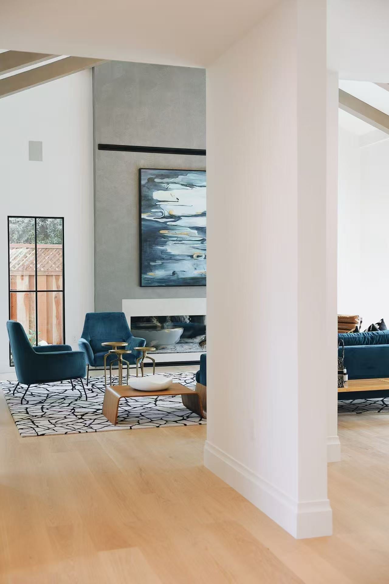 Living room sightline showing fireplace, artwork, and blue seating