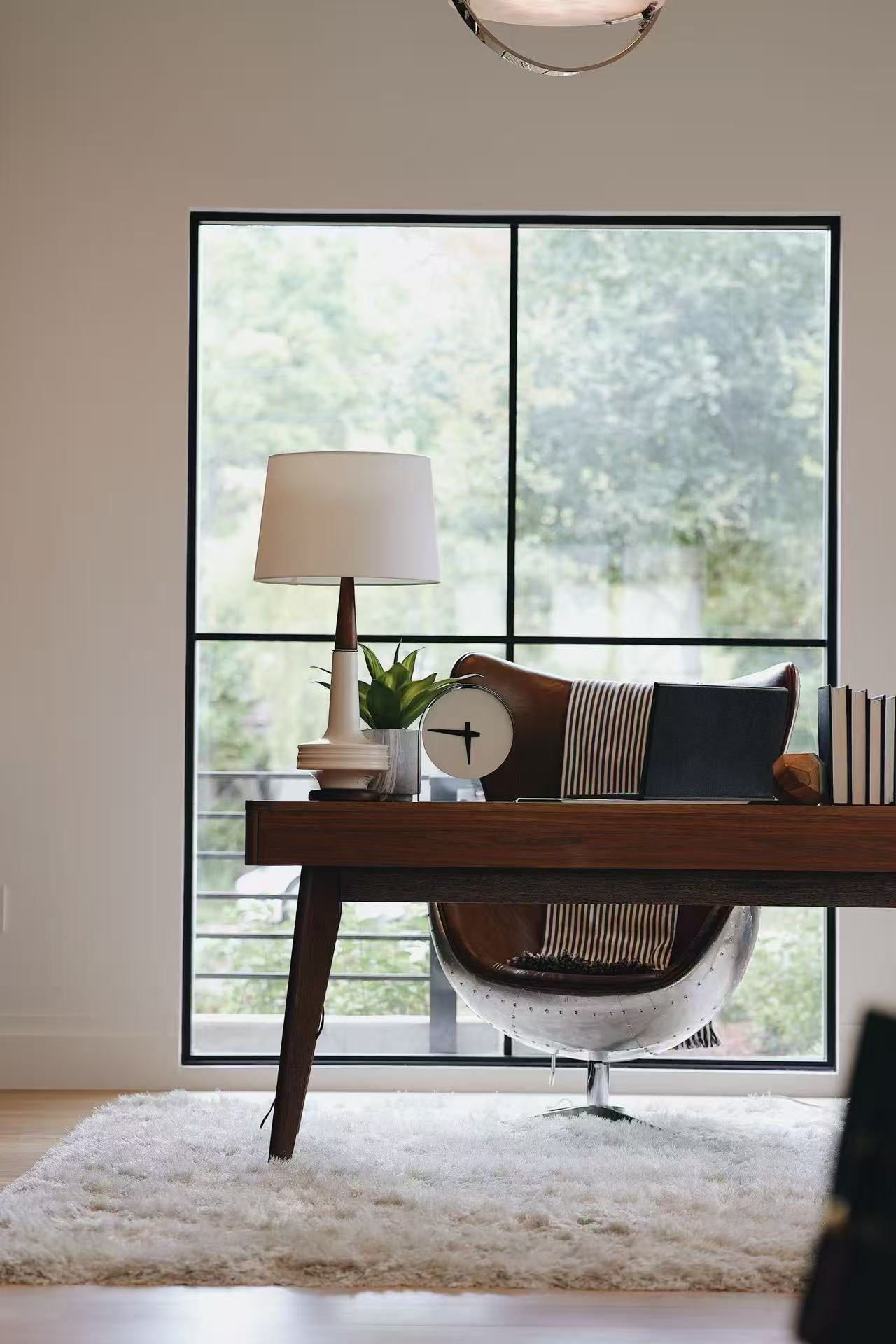 Study corner with wooden desk, lamp, and garden-facing window