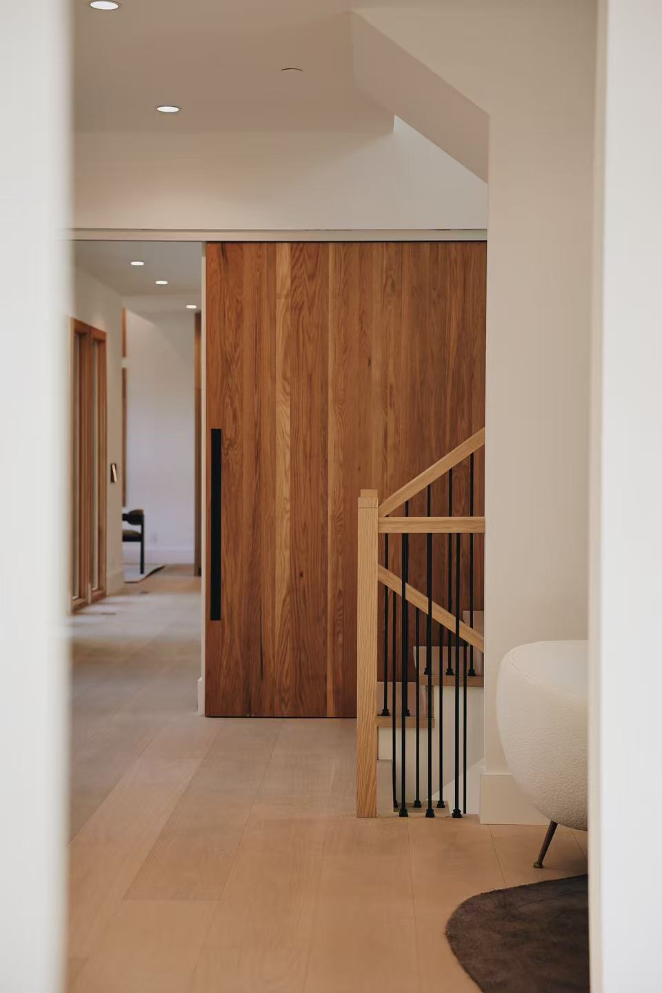 Stair and hallway view with glass railing and timber door