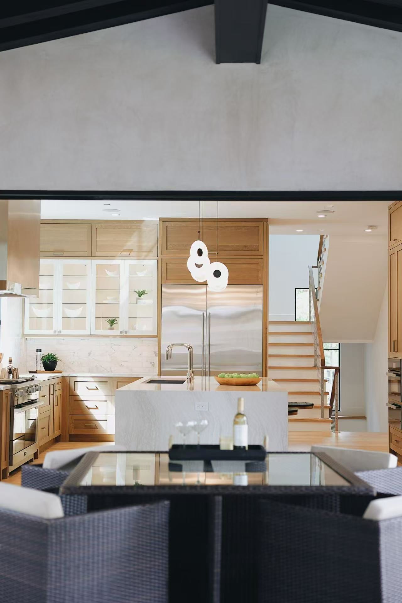 Covered patio view looking into the warm kitchen through black-framed folding doors