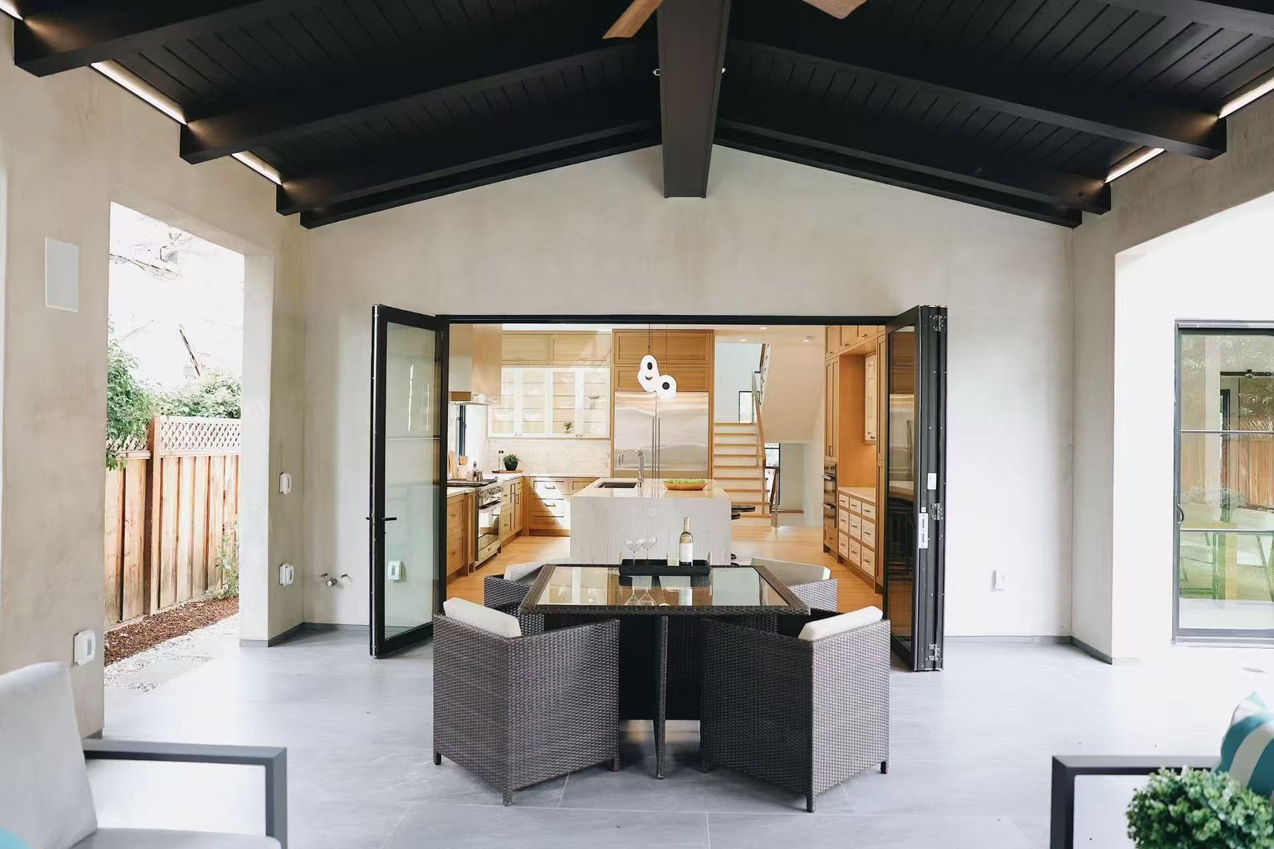 Outdoor entertaining area with dining table and open folding doors to the kitchen