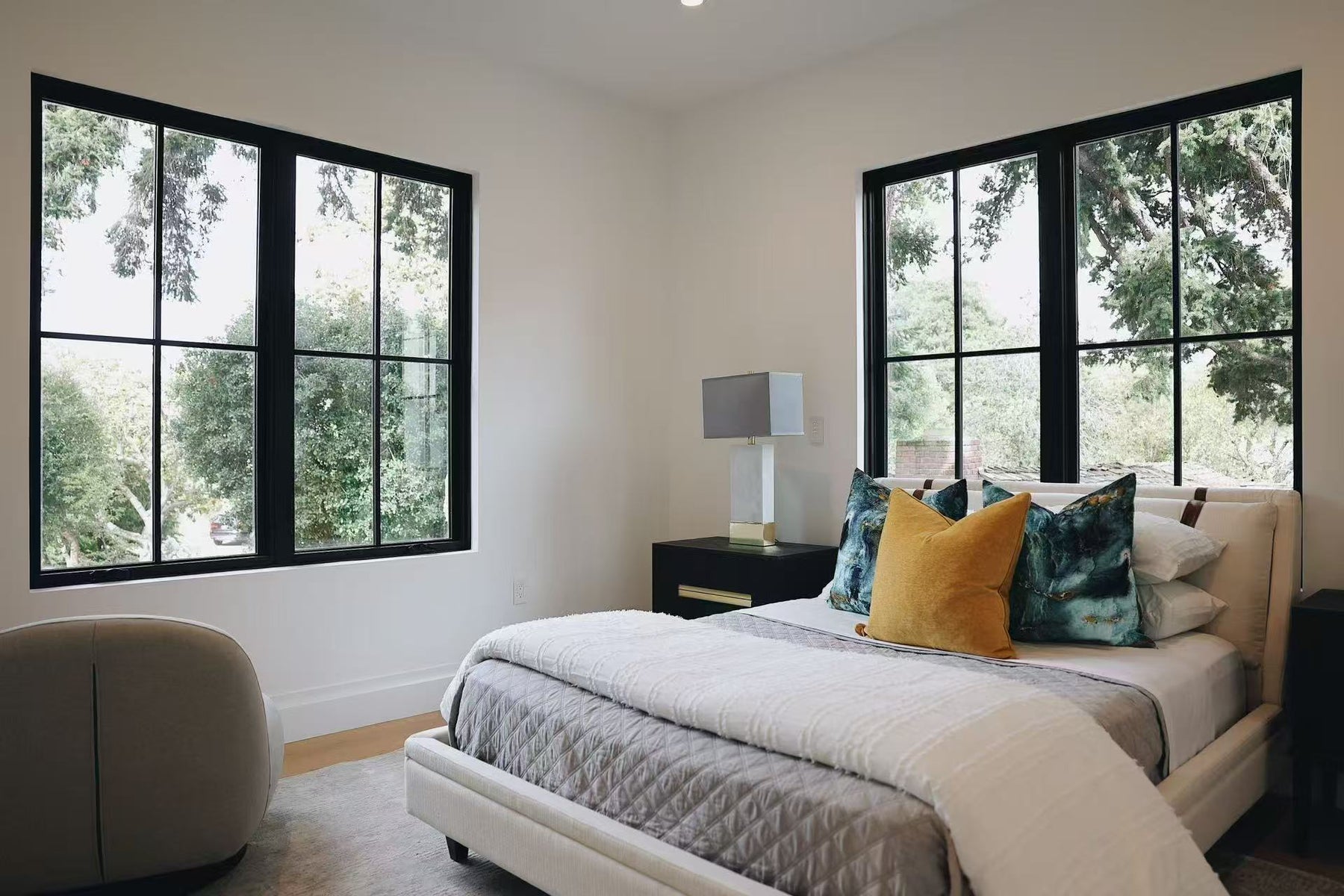 Bedroom with upholstered bed, black-framed windows, and colorful accent pillows