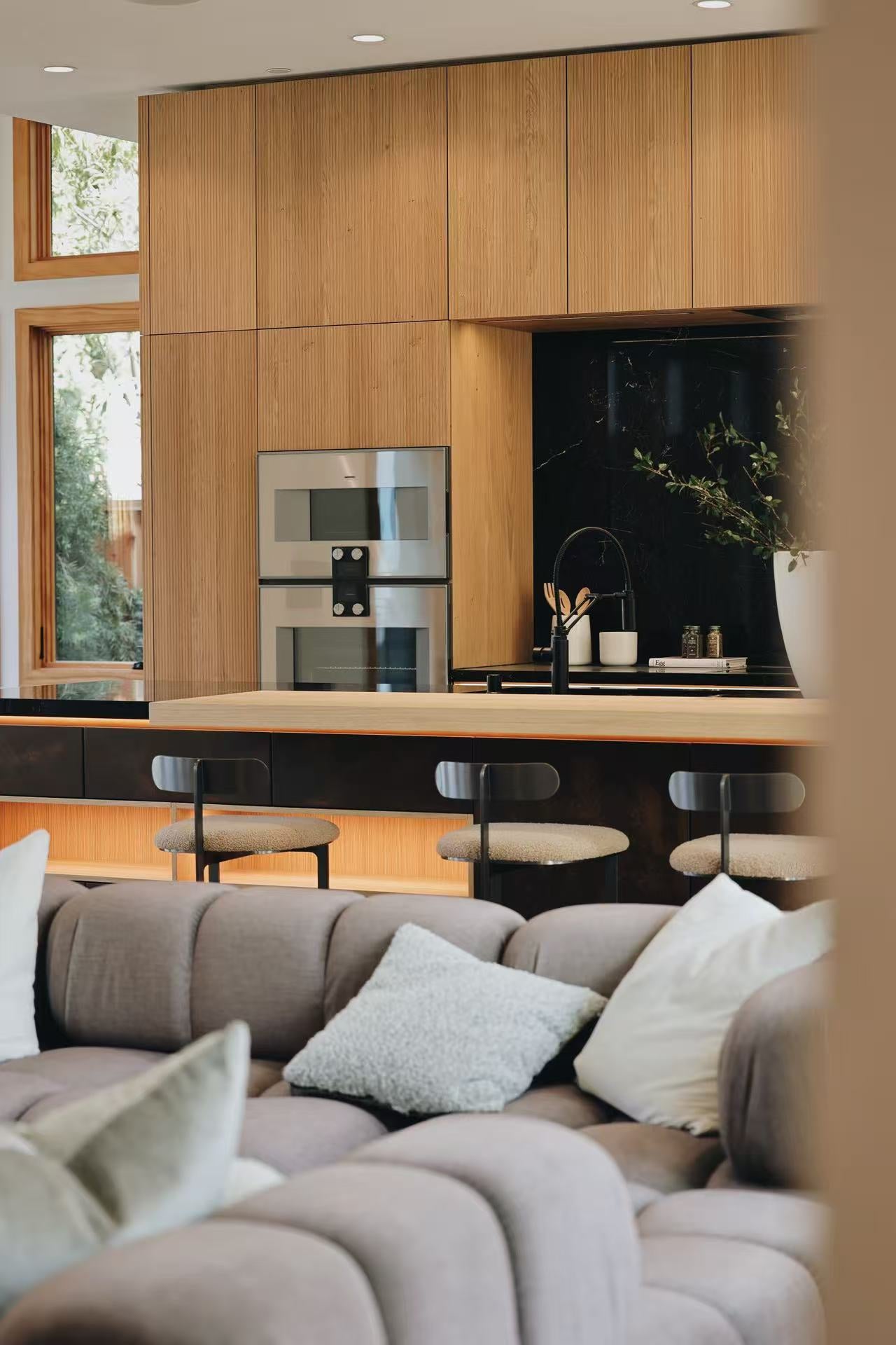 Living room sofa foreground with timber kitchen behind
