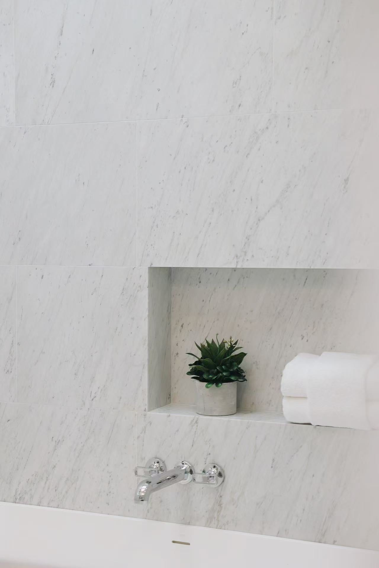 Marble-effect bathroom wall with shower niche and polished fixture