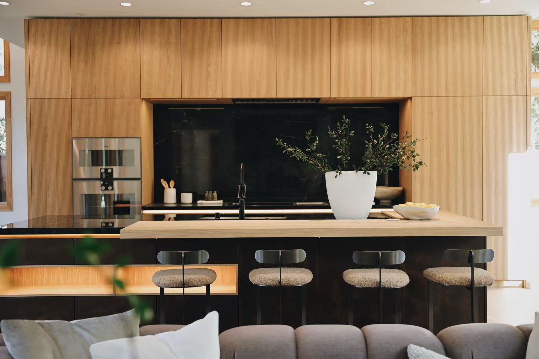 Kitchen and living area with island, stools, and warm timber panels