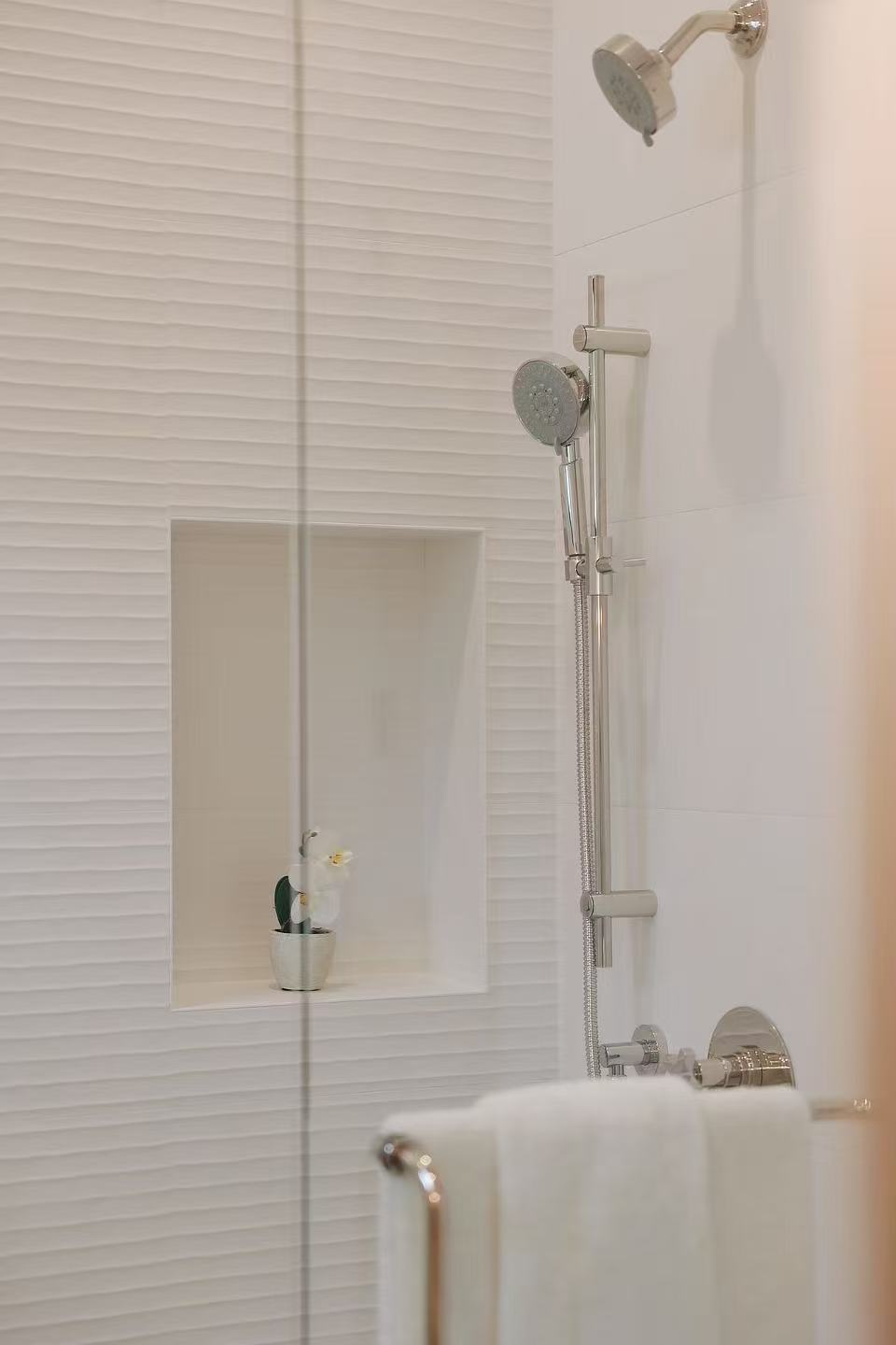Shower detail with glass panel, niche, and pale textured wall