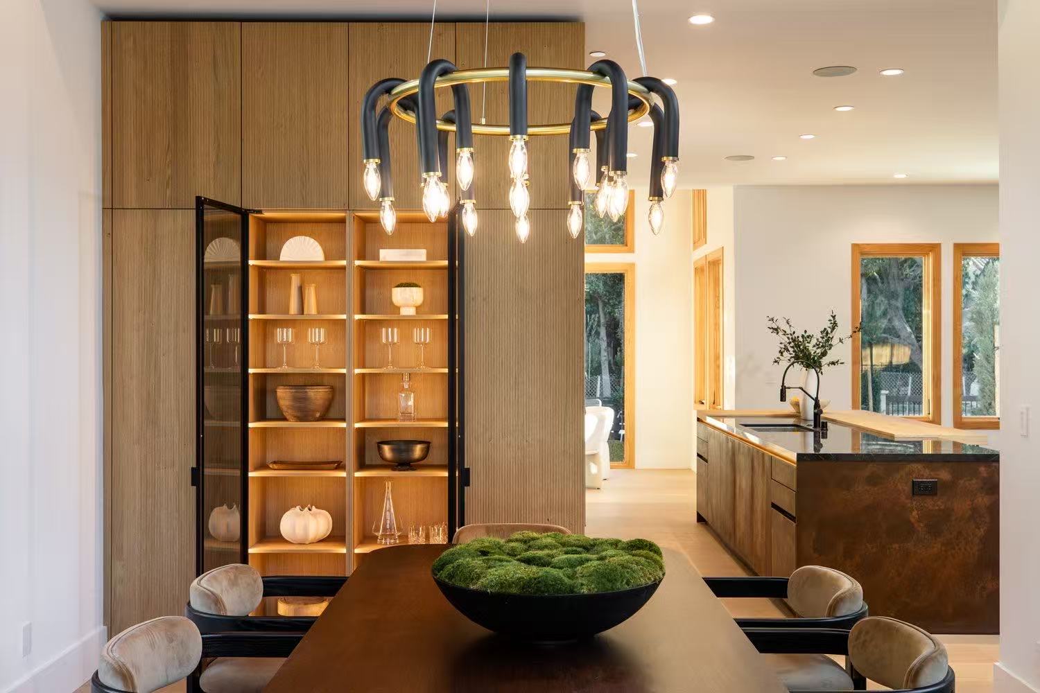 Dining and kitchen view with sculptural chandelier, timber storage, and island