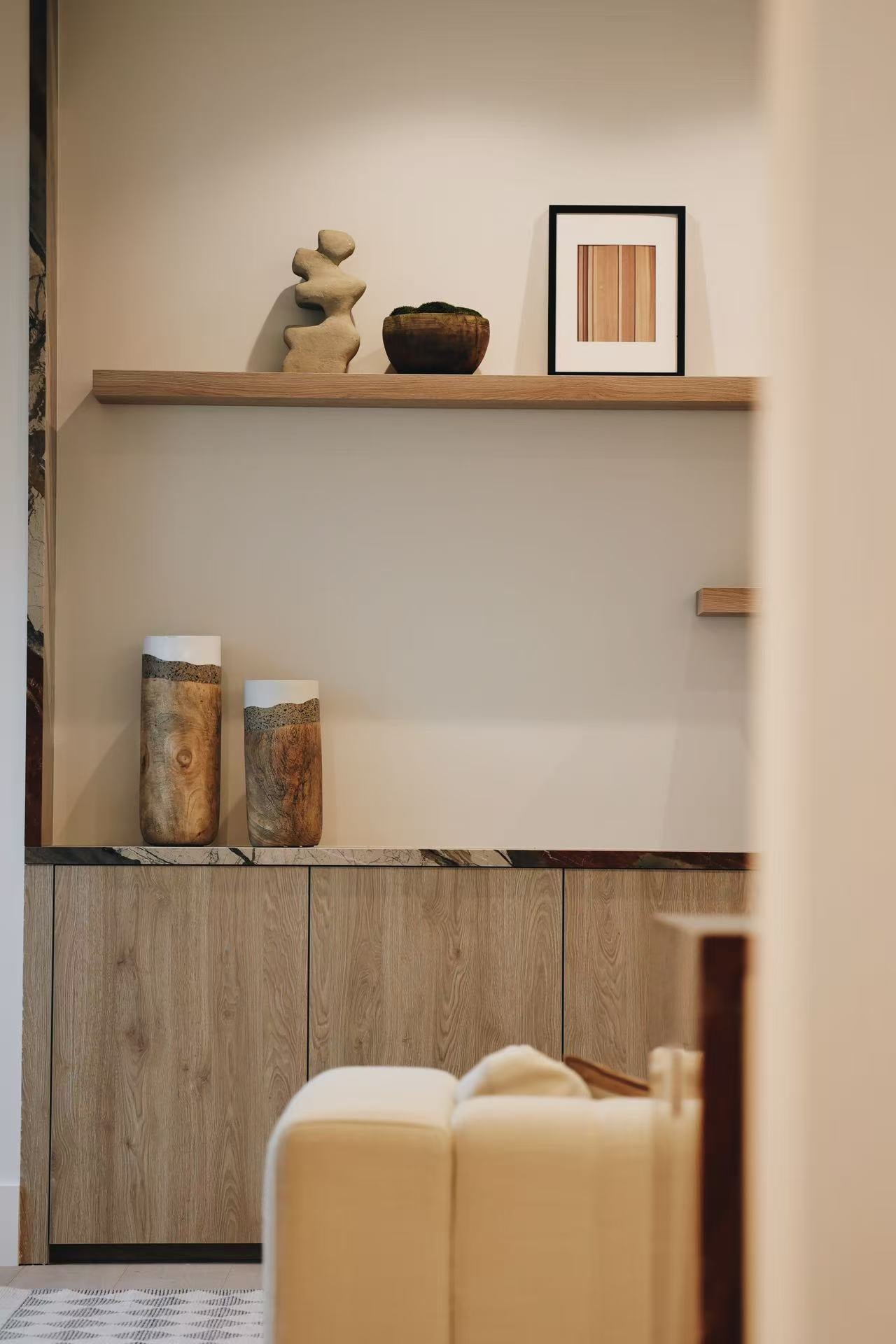 Built-in timber shelving with display objects and upholstered chair