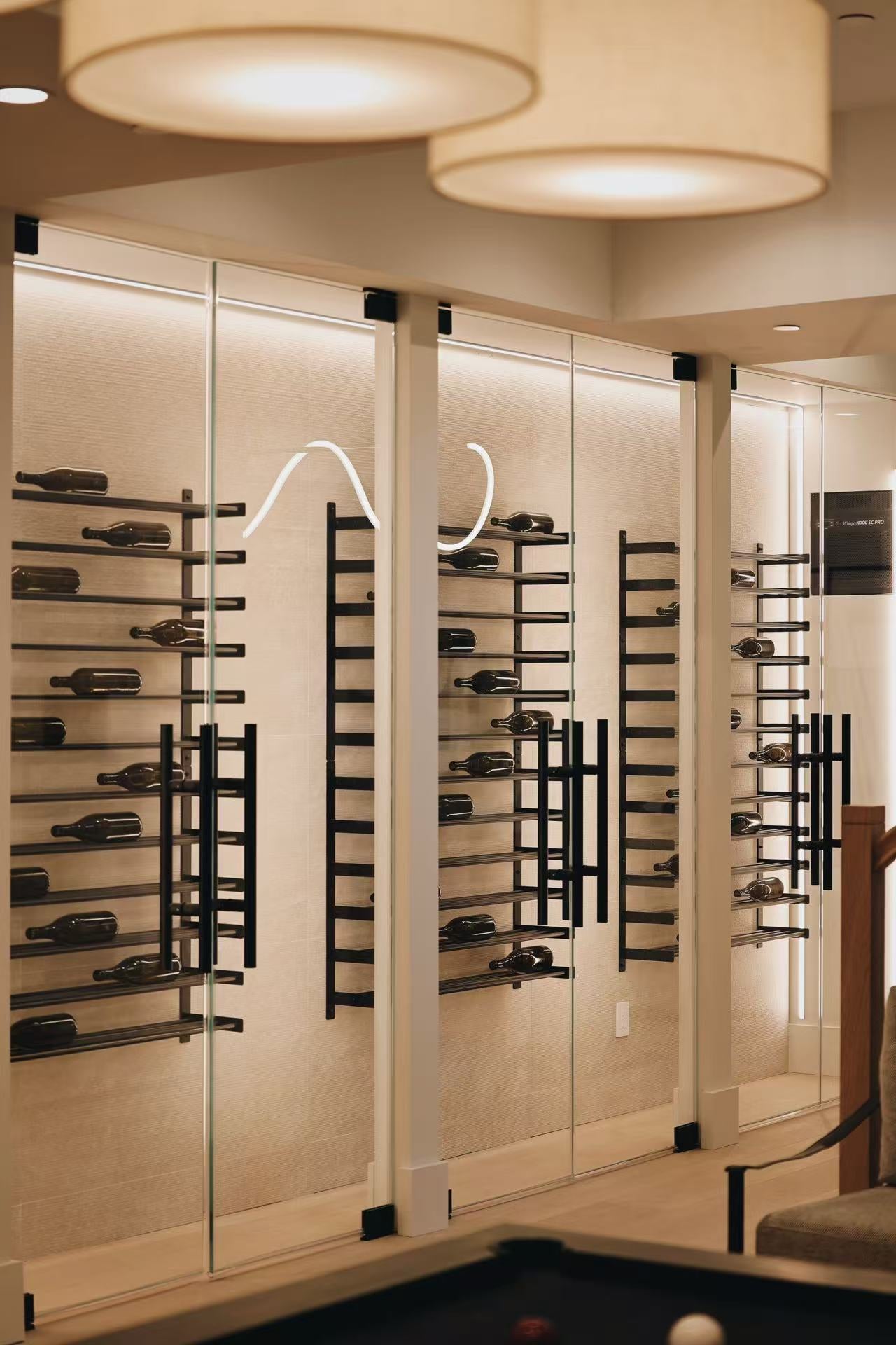 Wine display room with glass door, black metal racks, and warm ceiling lights
