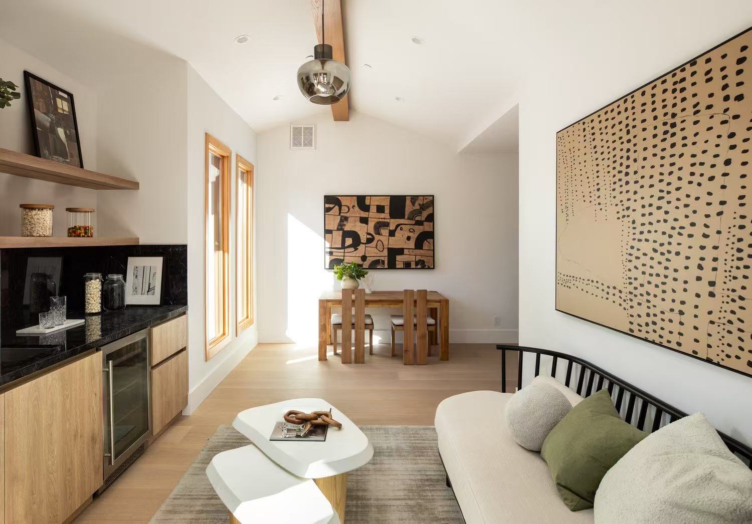 Bright lounge area with sectional sofa, art wall, and timber cabinet