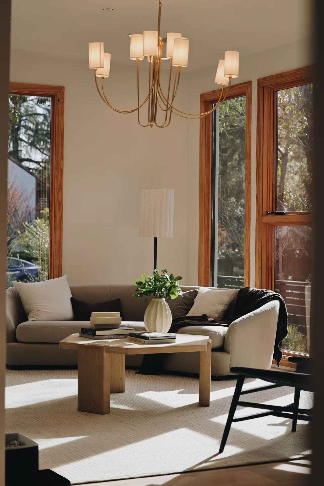 Lounge area with armchairs, chandelier, timber-framed windows, and coffee table