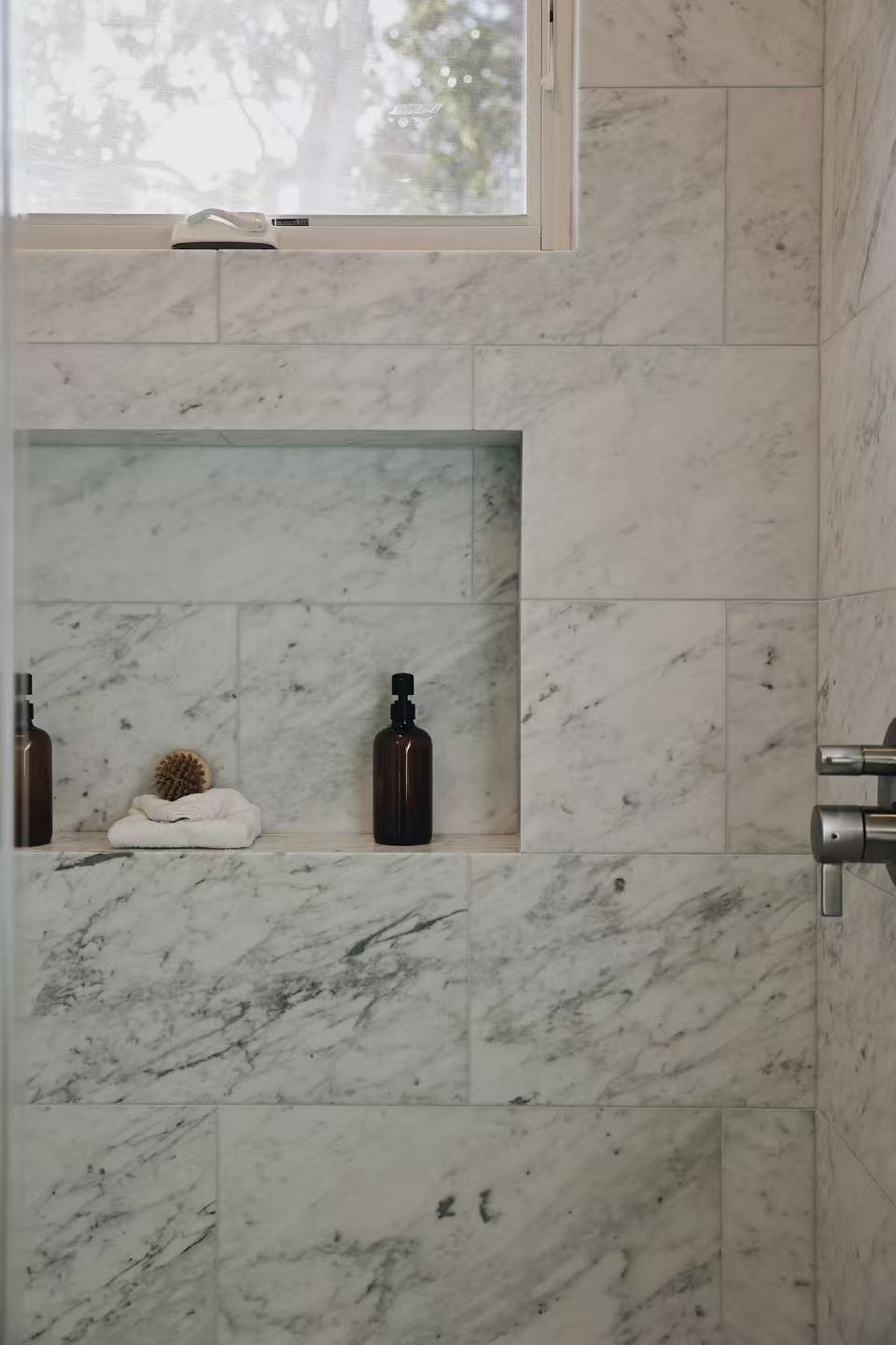 Bathroom shower detail with marble-effect stone wall and built-in niche