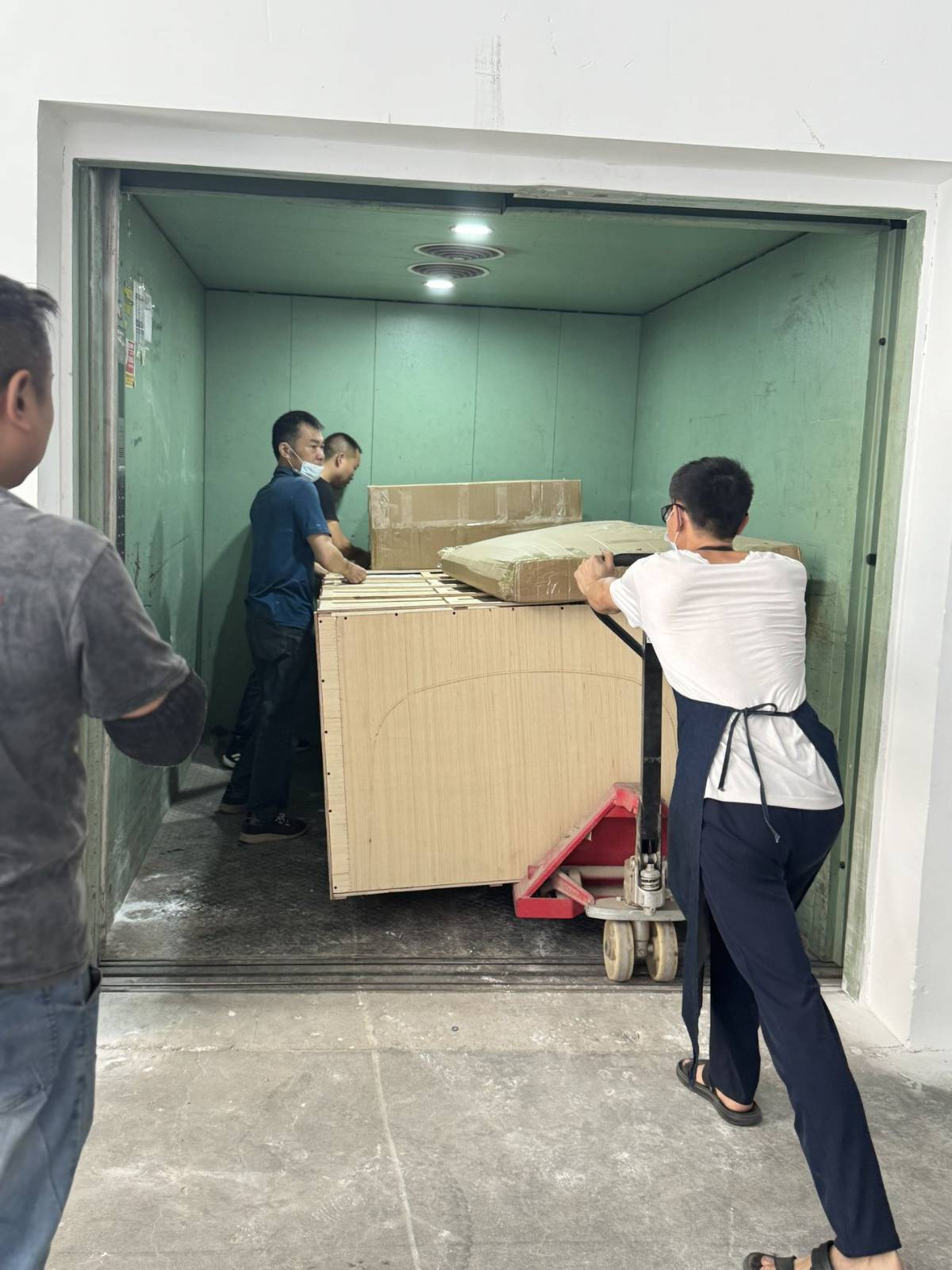 Packed furniture moved through freight elevator during delivery preparation