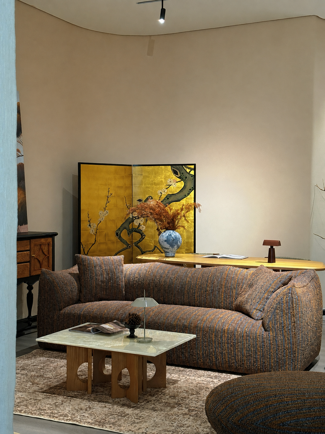 Pebbles warm living room with textured sofa, golden screen, and layered coffee table