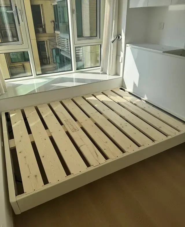 Pine bed frame with visible wood slat support in a sunlit bedroom