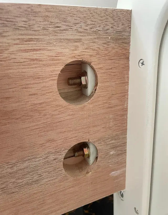 Close-up of bed frame board with half-moon screw connectors