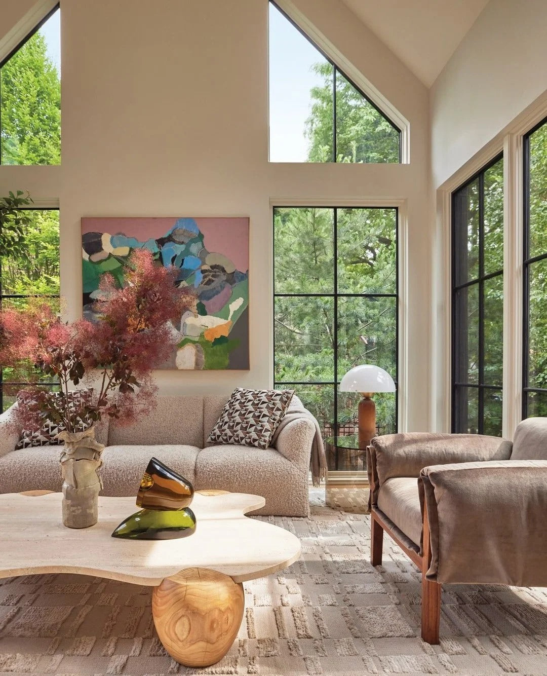 Soft neutrals feel richer when balanced with art, greenery, and sculptural tables.