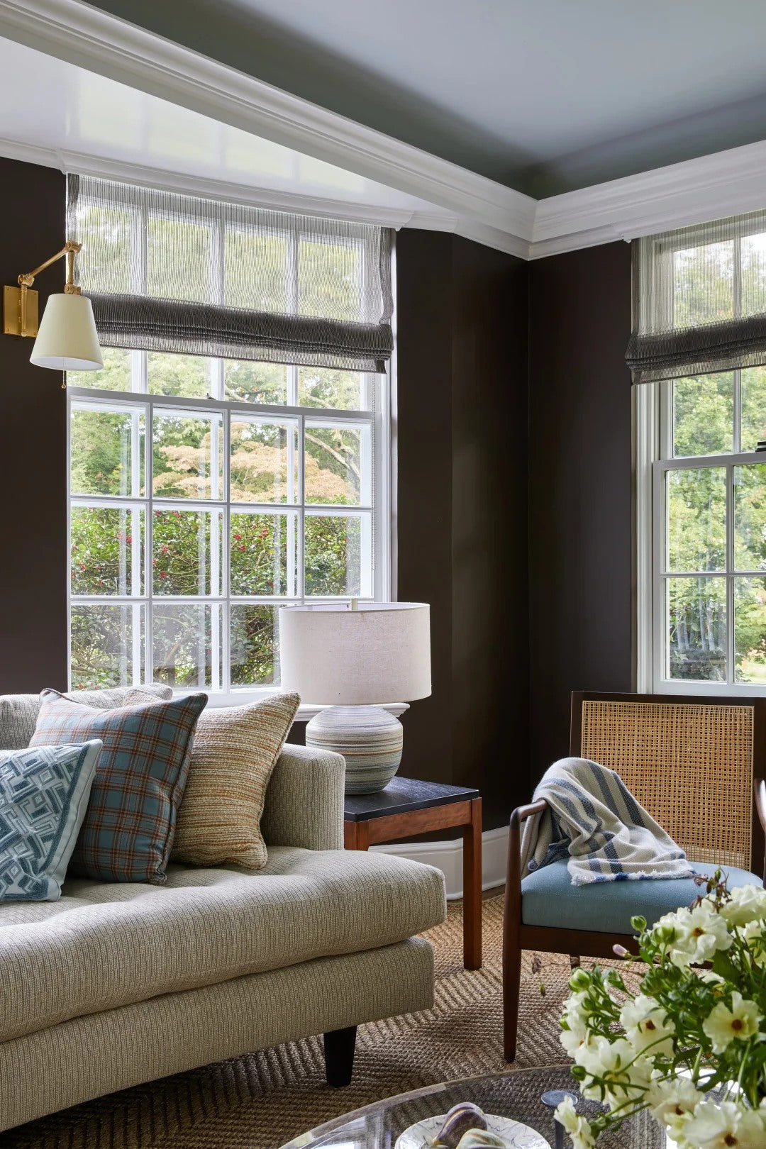 Dark walls make pale upholstery and patterned cushions feel more intentional.