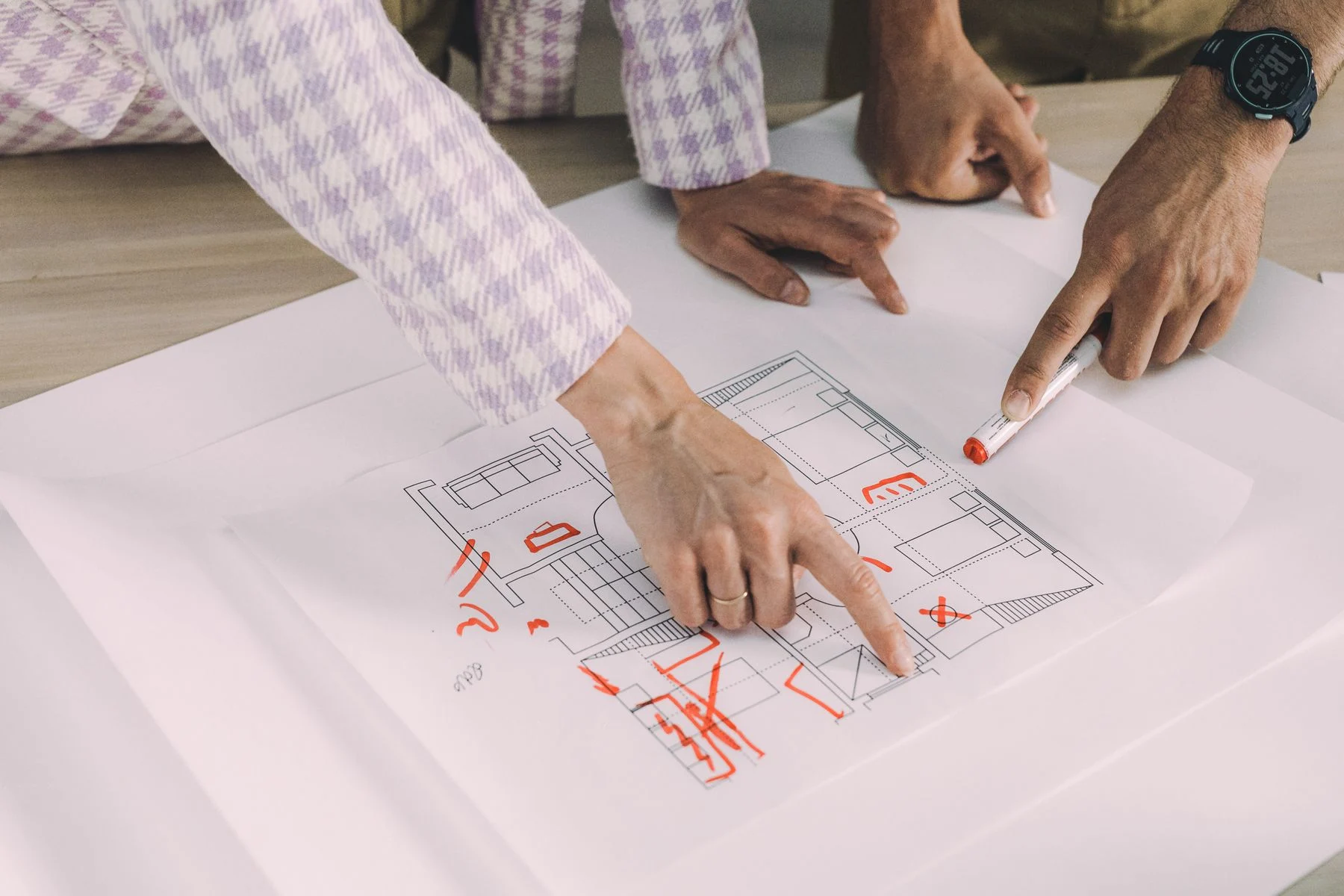 People reviewing and marking an architectural floor plan at a table