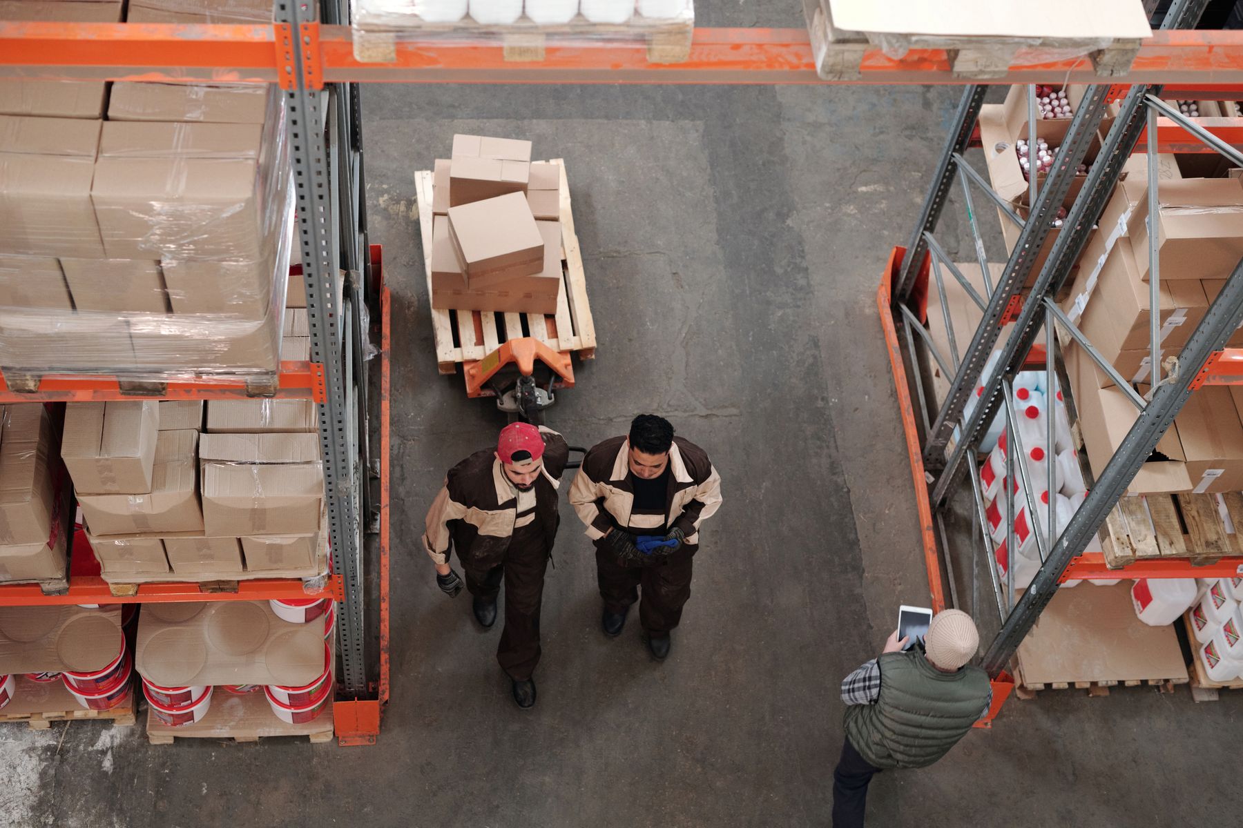 Warehouse workers organizing cartons and palletized goods for shipment