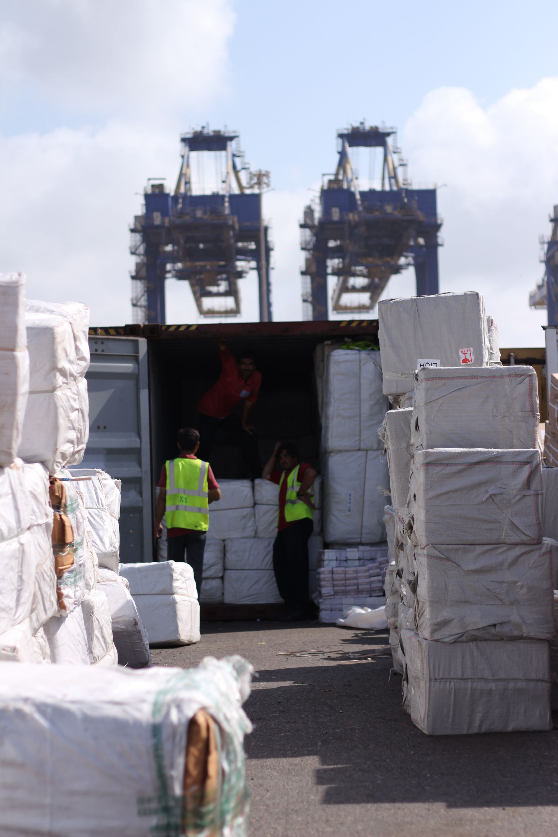 Port workers loading wrapped cargo packages into an open shipping container
