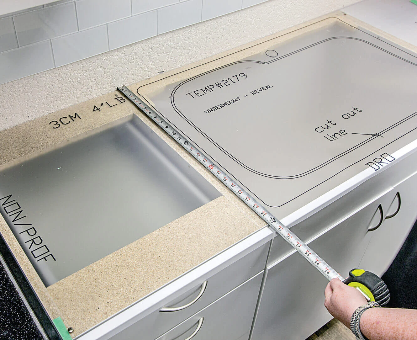 Tape measure positioned across a kitchen countertop with a marked sink cut-out template