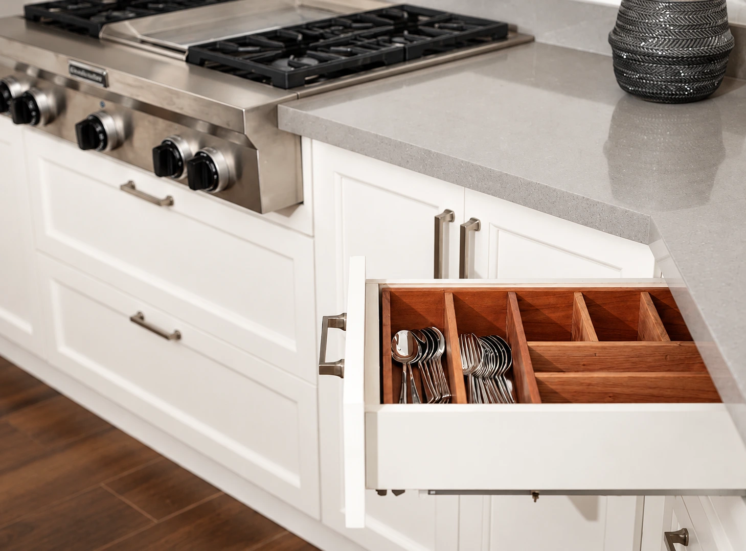 Open kitchen drawer with organised cutlery within reach beside a cooking area