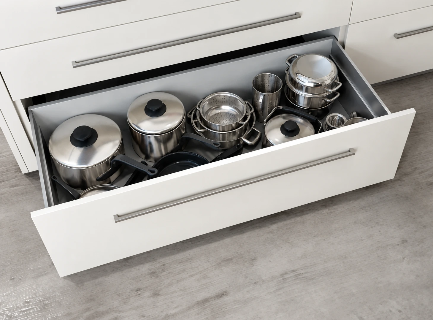 Deep kitchen drawer holding pots and pans with visible room around their handles