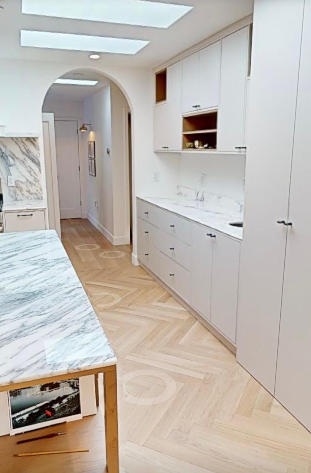 Coffee bar run with tall cabinets and open oak niches beside the arched hallway