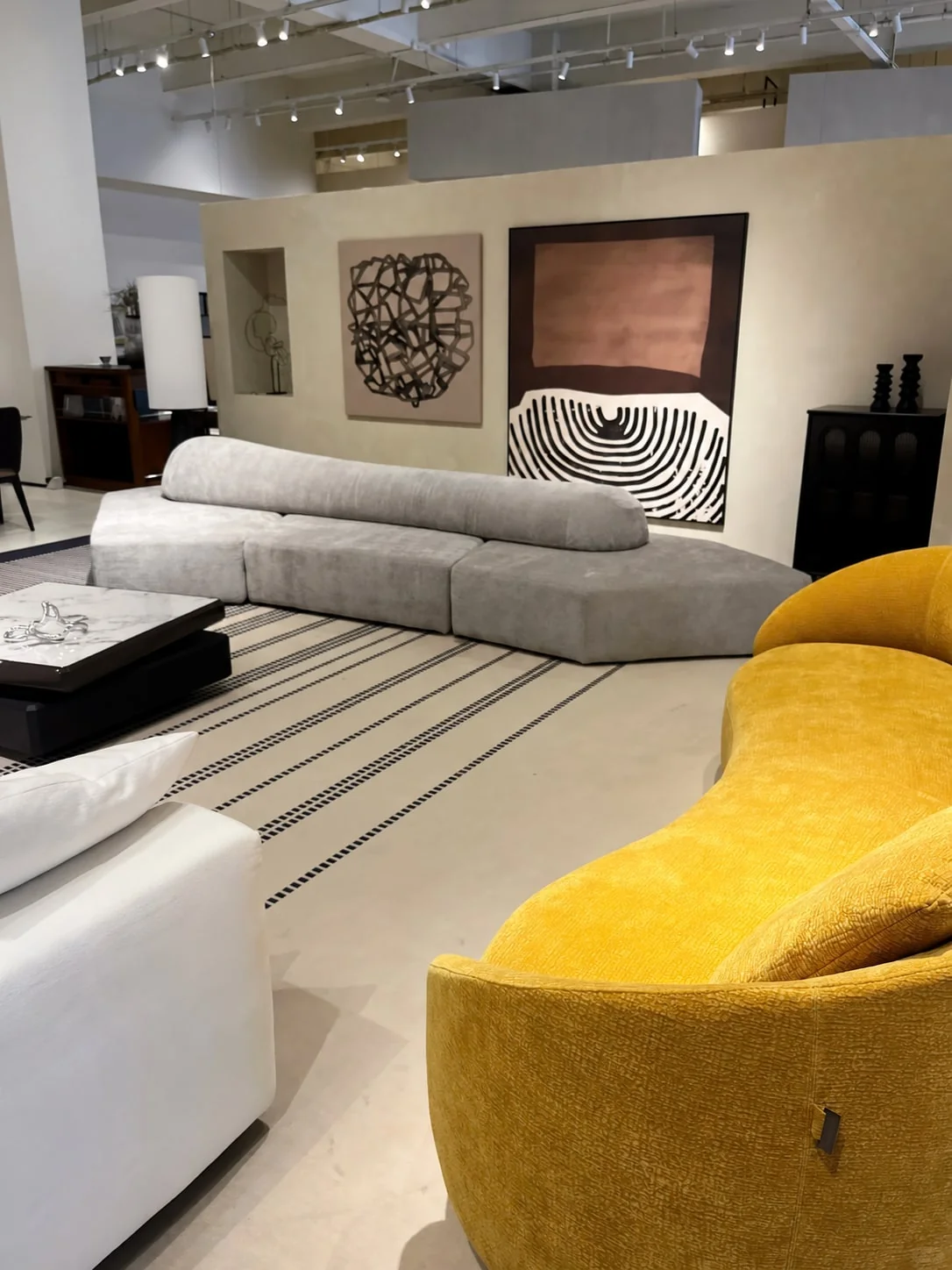 Grey upholstered sofa and mustard-yellow lounge chair in a showroom