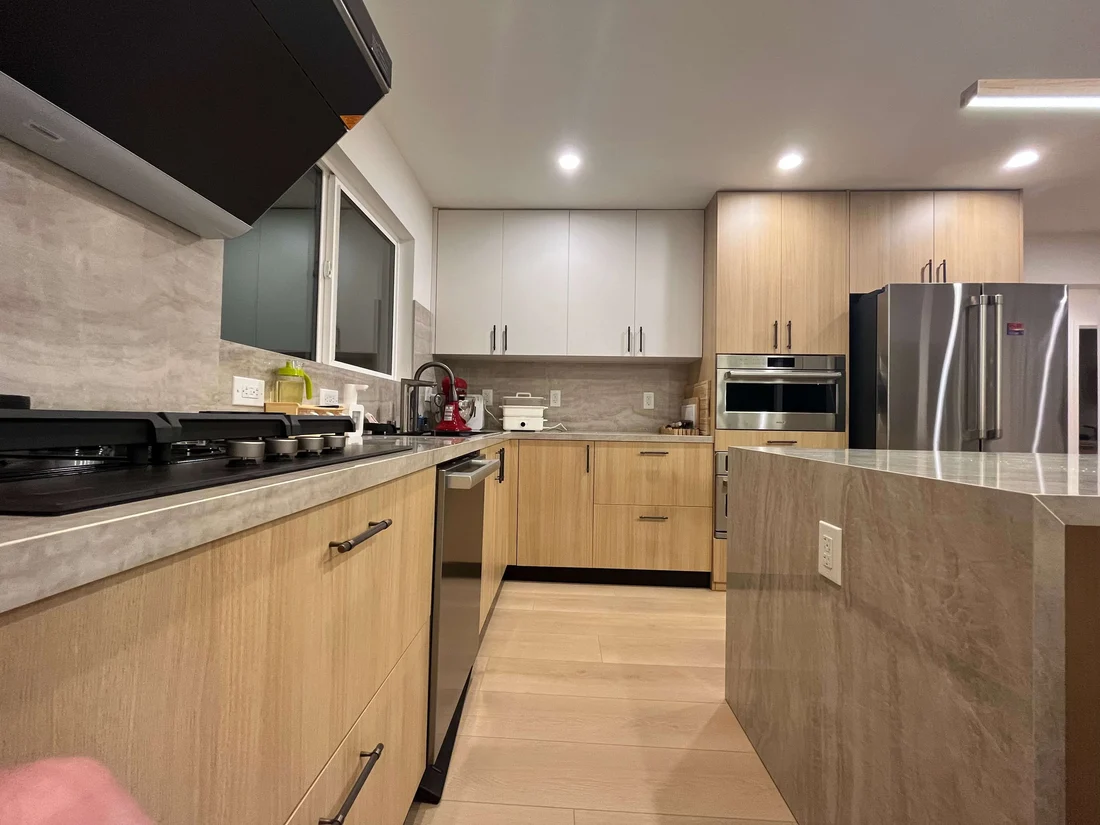 Completed San Jose kitchen looking along the cooking run to the oven stack, refrigerator and stone island