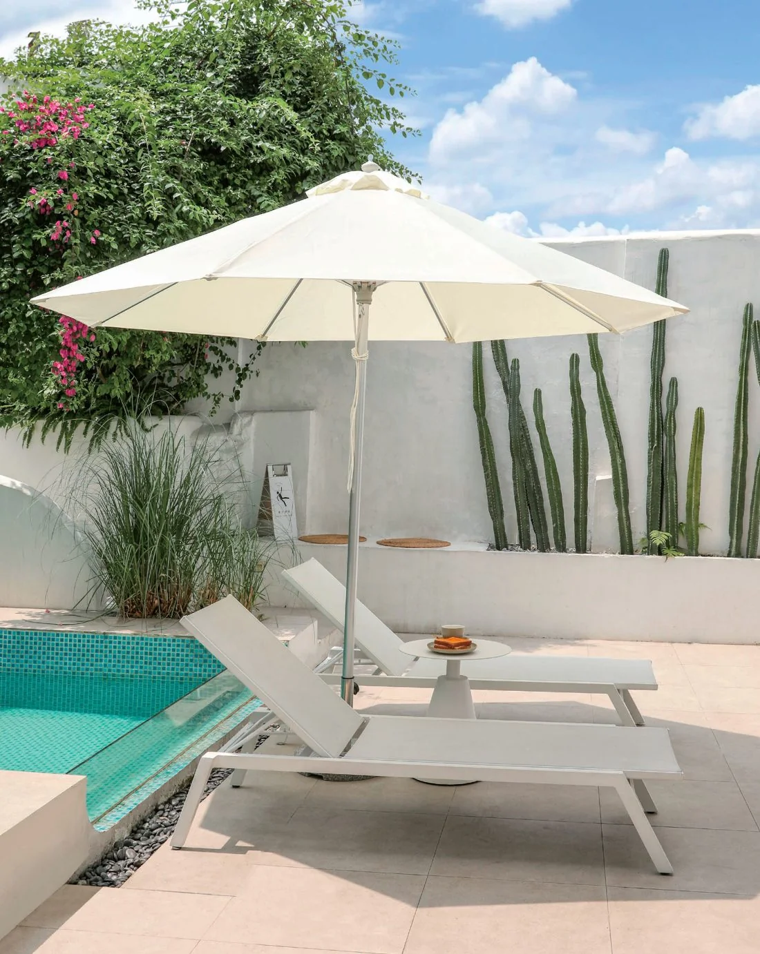 Pair of white sling loungers beneath an umbrella