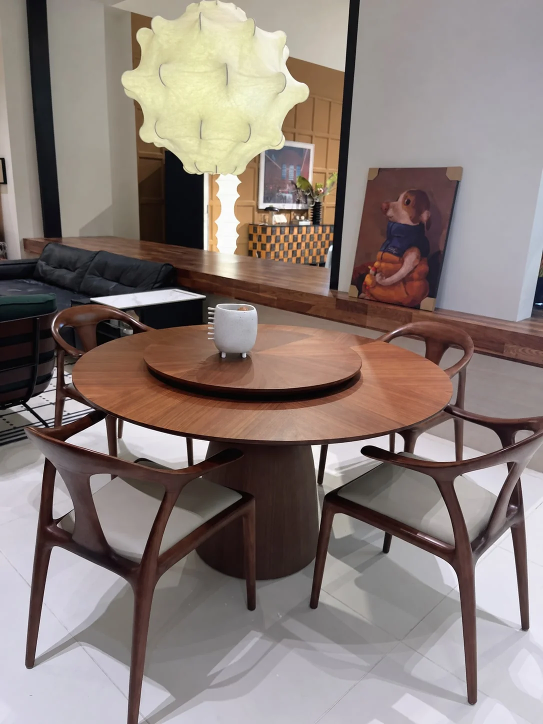 Round timber dining table with a rotating centre tray and curved dining chairs