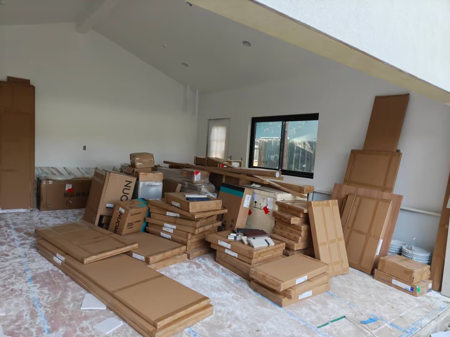 The full kitchen consignment unloaded and staged in an adjoining room, panels and boxes labelled