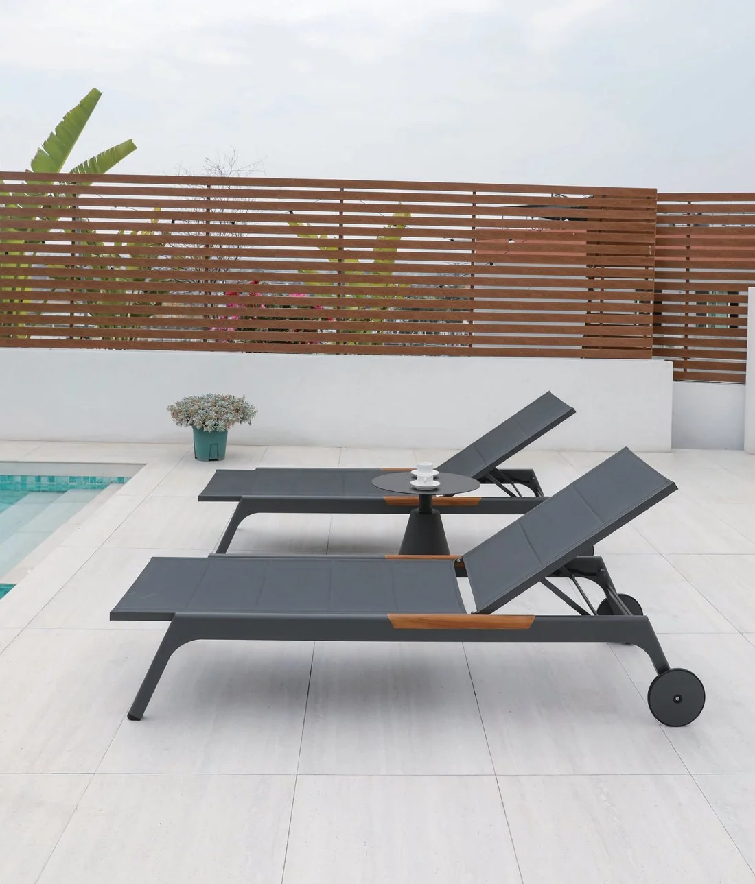 Dark wheeled loungers on a pool deck